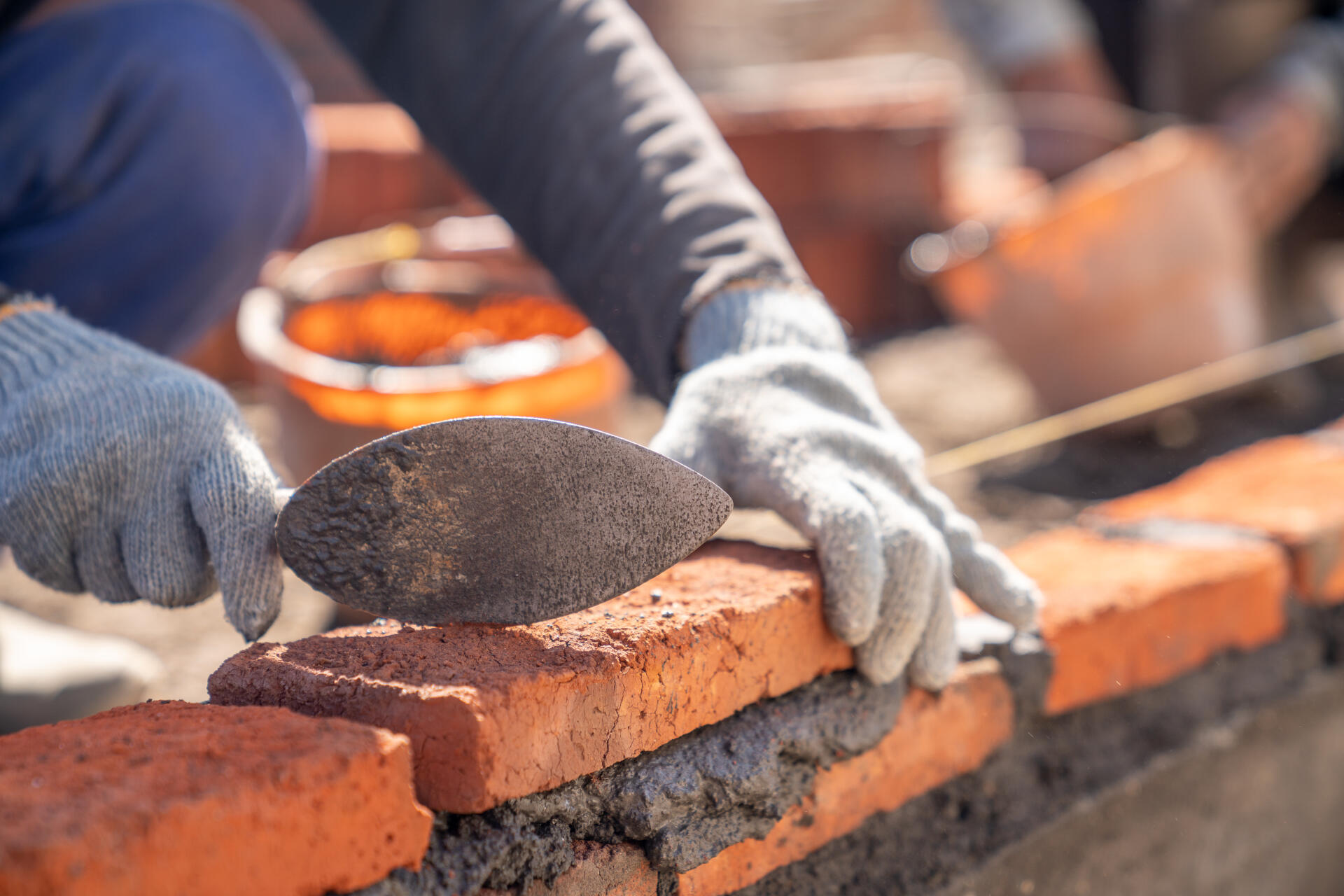 Maçon posant des briques à la truelle sur un chantier de construction